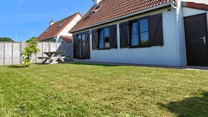 Et etplanshus med rødt tegltag, hvide ydermure og mørke markiser for vinduerne.