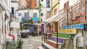 A narrow courtyard with a staircase leading to a second floor, surrounded by buildings with balconies and outdoor seating. - Belvilla by OYO Schembri Appartement (Agrigento)