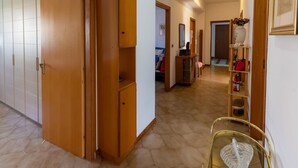 A hallway with wooden doors, a glass table with a decorative item, and a fire extinguisher on the floor. - Belvilla by OYO Schembri Appartement (Agrigento)