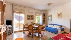A living room with a dining area, a TV, a bookshelf, and a sofa. - Belvilla by OYO Schembri Appartement (Agrigento)