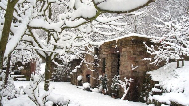 A stone building with a snow-covered roof and walls, surrounded by snow-laden trees and a snow-covered ground. - Pfaelzerleben (Oberotterbach)