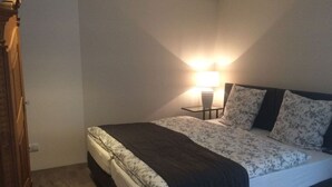 A bedroom with a bed, a bedside table with a lamp, and a wardrobe. - Pfaelzerleben (Oberotterbach)
