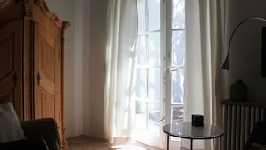 A room with a wooden wardrobe, a table with a black object, and a radiator. - Pfaelzerleben (Oberotterbach)
