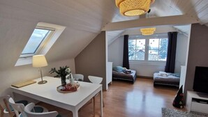A loft-style living space with a dining area, a sofa, a TV, and a window with a view of trees. - Holiday Home "schwedenhaus Bad Tabarz" (Tabarz)