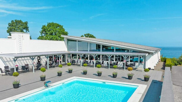 A modern hotel with a pool, outdoor seating, and a view of the sea. - 1 Person Holiday Home in Allinge (Allinge)