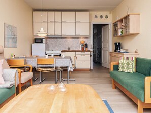 A compact living space with a dining area, kitchenette, and a green sofa. - 4 Person Holiday Home in Fano (Fano)