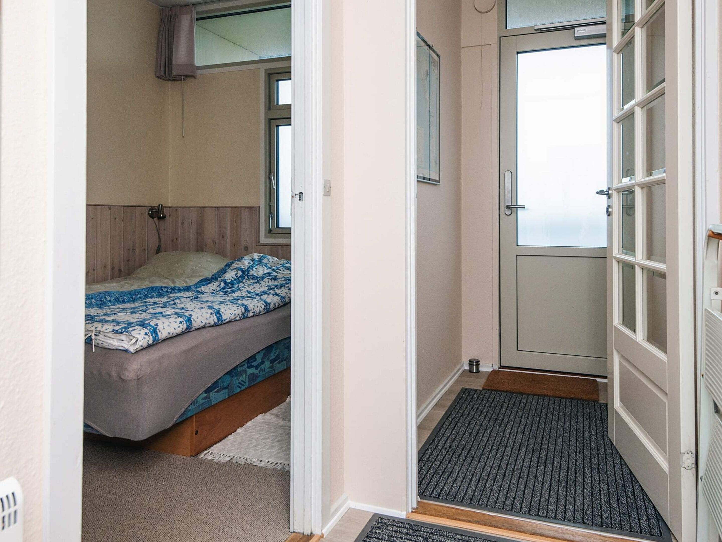 A bedroom with a bed, a window, and a door leading to a balcony.