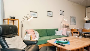 A modern living room with a green sofa, black leather chair, wooden coffee table, and a small side table with a lamp. - 4 Person Holiday Home in Fano (Fano)