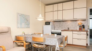 A compact kitchen with a dining area, featuring a map on the wall, a microwave, a stove, and a sink. - 4 Person Holiday Home in Fano (Fano)