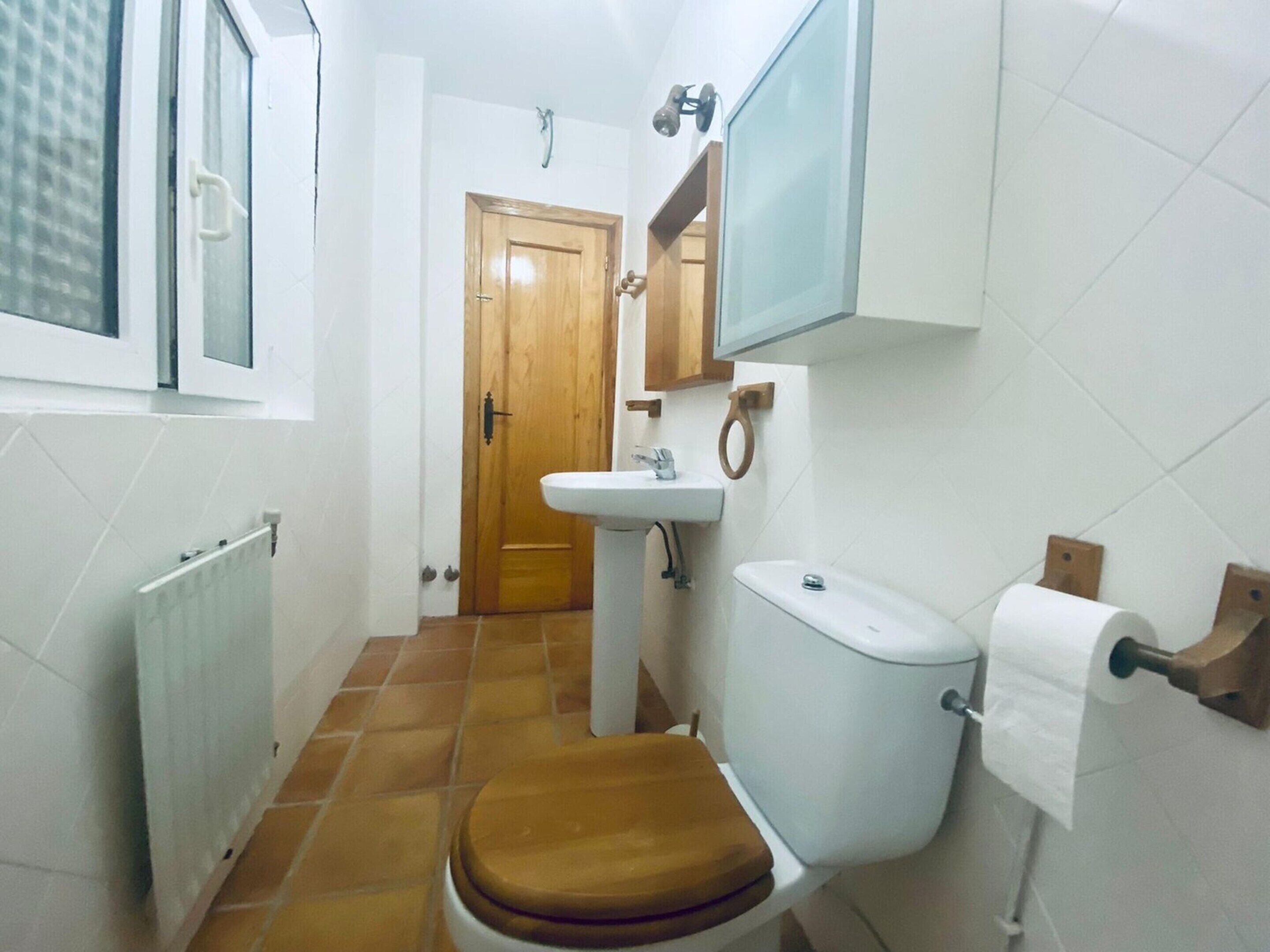 A small bathroom with a toilet, sink, and window.