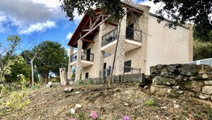 A two-story building with a stone facade, balconies, and a stone retaining wall.