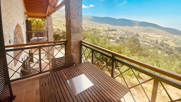 A wooden deck with a metal railing overlooking a mountainous landscape.