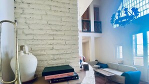 A spacious living area with a white brick wall, a large white vase, a brass floor lamp, a sofa, and a coffee table.