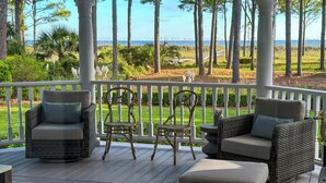 A covered outdoor area with wicker furniture, a white railing, and a view of the ocean. - 21 Painted Bunting at The Sea Pines Resort (Hilton Head Island)