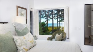 A bedroom with a large bed, a chair, a window with a view of trees and a body of water. - 21 Painted Bunting at The Sea Pines Resort (Hilton Head Island)