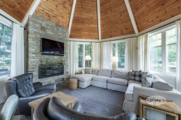 A cozy living room with a stone fireplace, leather sofas, and large windows. - 7 bed, 5 bath spectacular cottage on Lake Joseph! (Parry Sound Mid-Shore (Bala))
