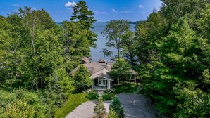 Une maison entourée d’une forêt dense, avec vue sur un lac.
