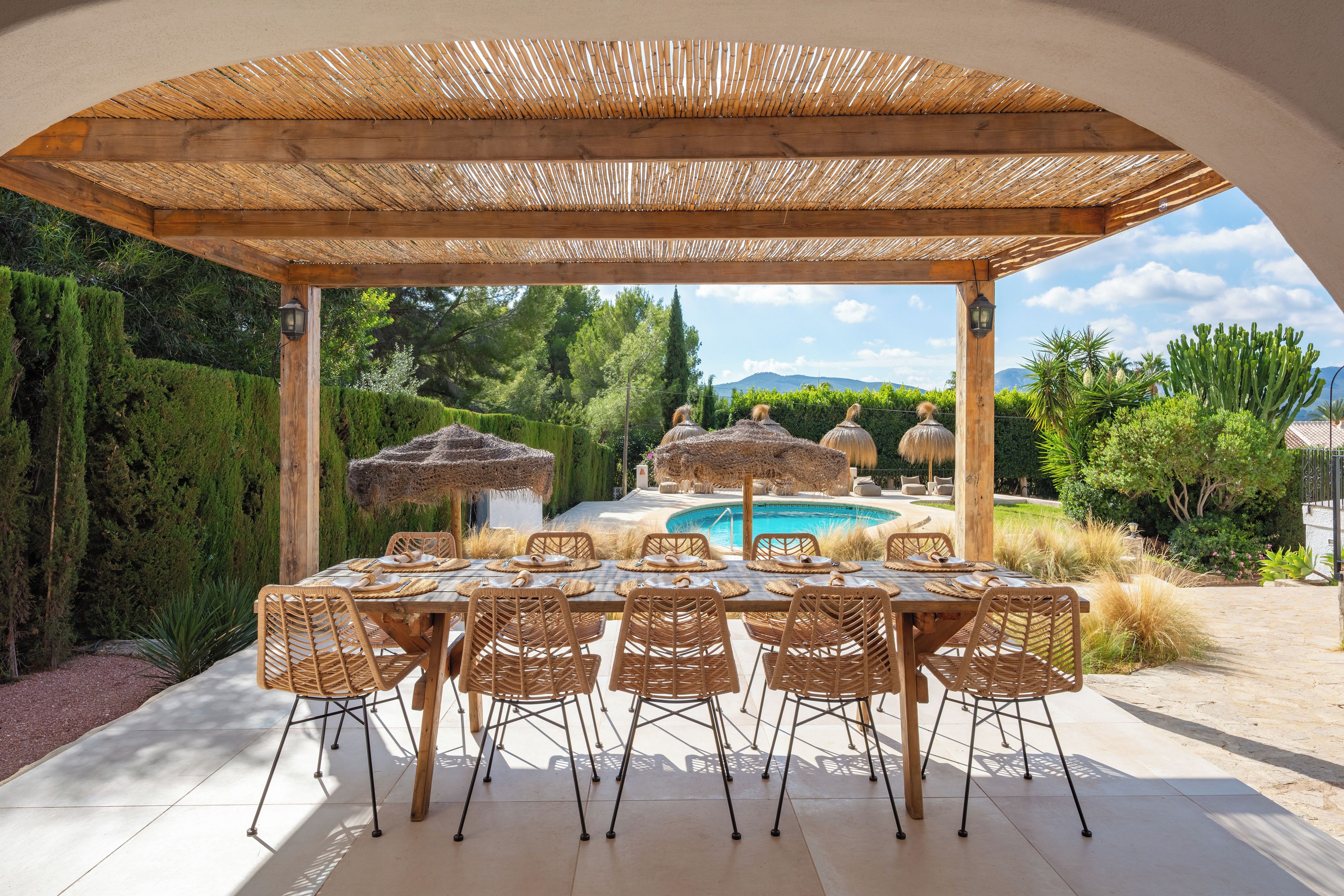 An outdoor dining area with a pergola, a pool, and a view of the mountains.