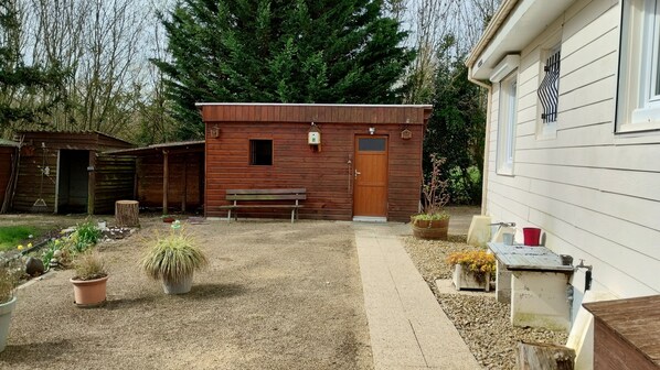 A rustic wooden cabin with a bench and potted plants in the yard. - La Petite Cabane au Coeur du Marais Poitevin (Maillé)