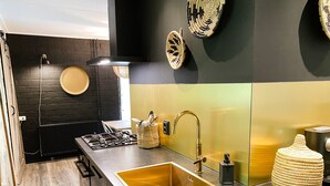 Una cocina moderna con un lavamanos de acero inoxidable, una estufa a gas y una pared de ladrillo negro.