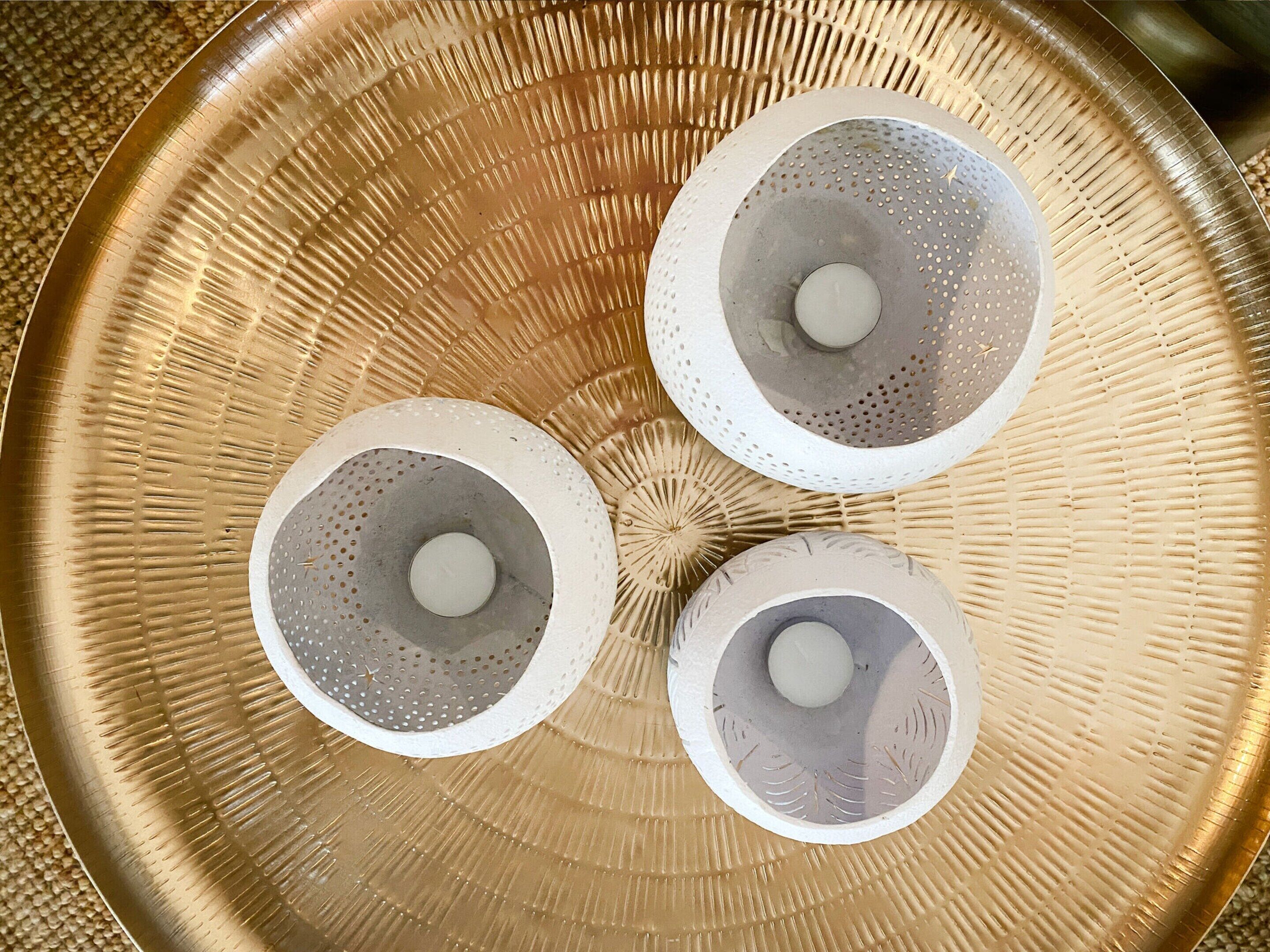 A round, textured tray with three perforated bowls on it.
