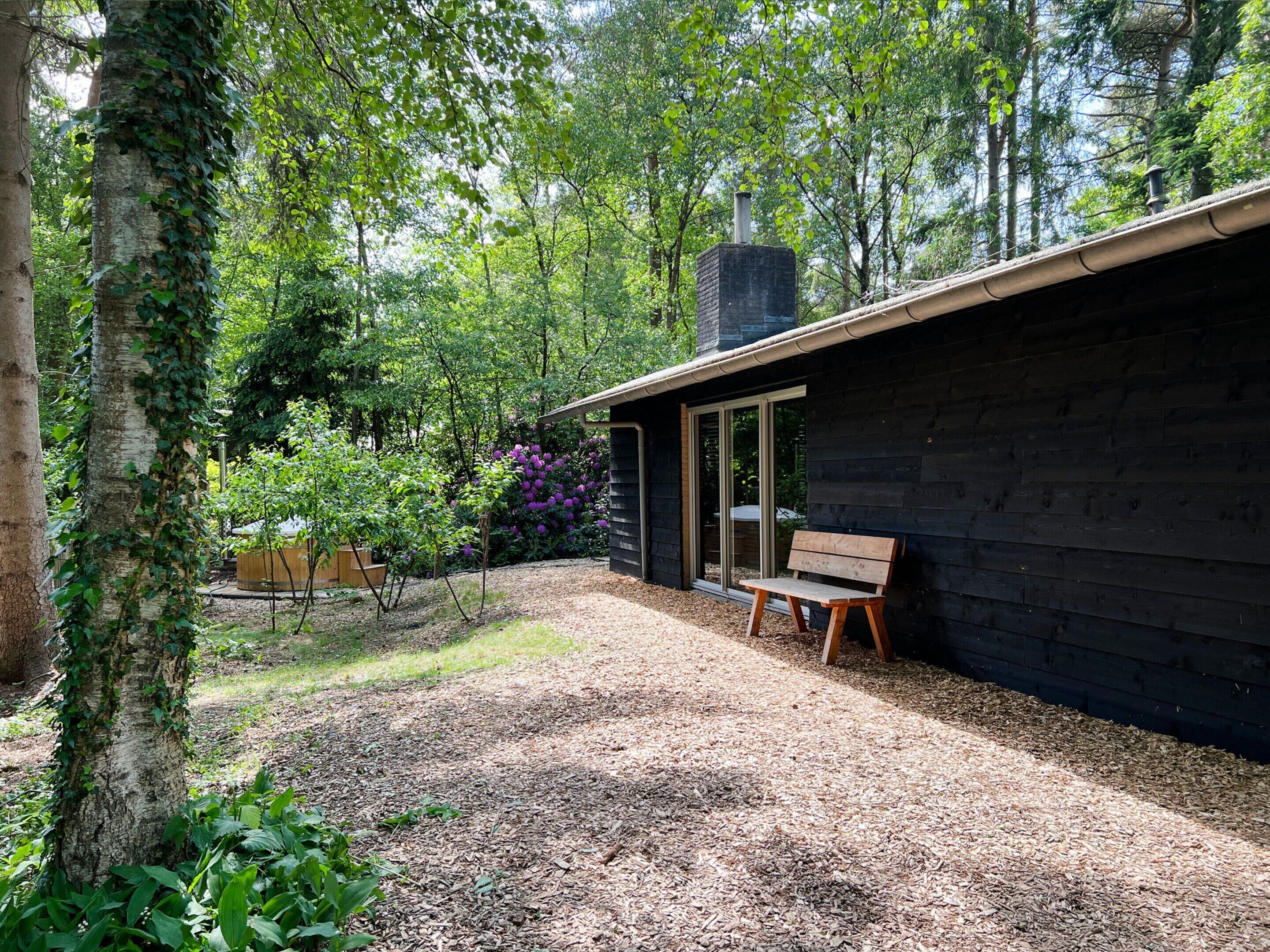 Une cabane dotée d’une terrasse en bois, d’un banc et d’une cheminée.