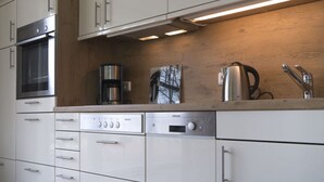 Una cocina moderna con electrodomésticos de acero inoxidable, armarios de madera y una cafetera integrada.