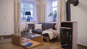 Una sala de estar moderna con una mesa de centro de vidrio, un sofá, una chimenea y ventanas grandes con cortinas.
