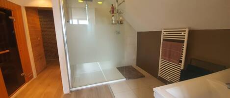 Un baño moderno con cabina de ducha de vidrio, una bañera blanca y suelo de madera.