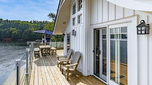 Eine Holzterrasse mit Sitzgelegenheiten und Blick auf das Wasser.