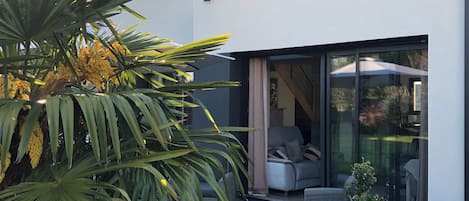 A modern house with a patio area, outdoor furniture, and a large window.