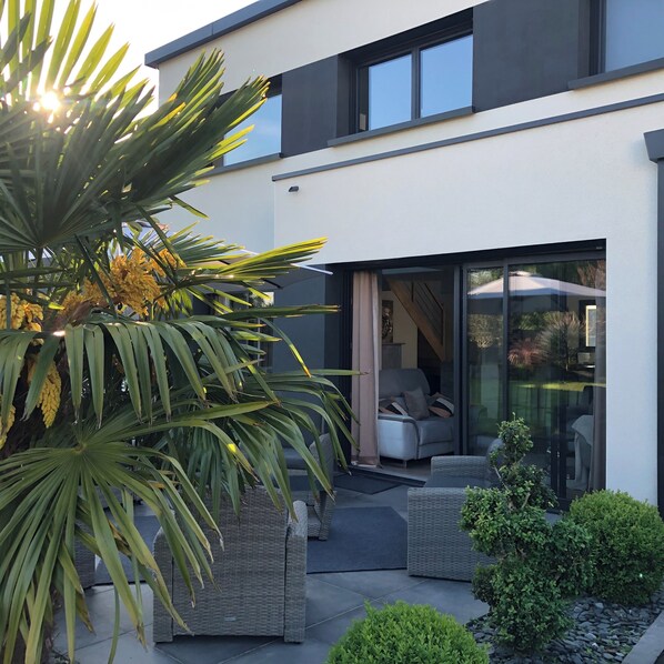 A modern house with a patio area, outdoor furniture, and a large window.