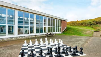 A chessboard set up on a paved area in front of a building with large windows.