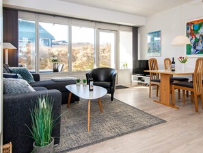Een moderne woonkamer met een bank, salontafel en eethoek.