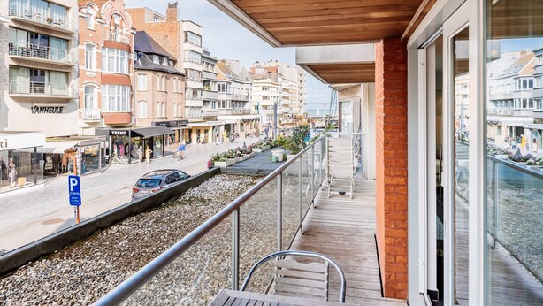 A balcony with a view of a city street, a parking sign, and a building with a sign that reads "VANHEULE". - Apartment in Belgium 100m From the Sea (Koksijde)