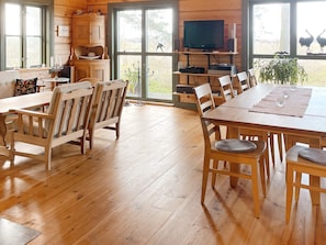 A spacious dining area with wooden furniture, a television on a stand, and a view of the outdoors through large windows. - 4 Star Holiday Home in Yngsjo (Yngsjo)