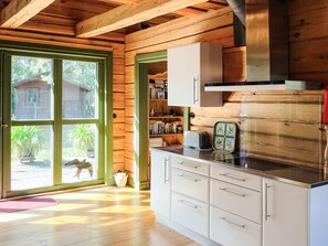 A wooden cabin interior with a kitchen area, a bookshelf, and a view through a glass door. - 4 Star Holiday Home in Yngsjo (Yngsjo)