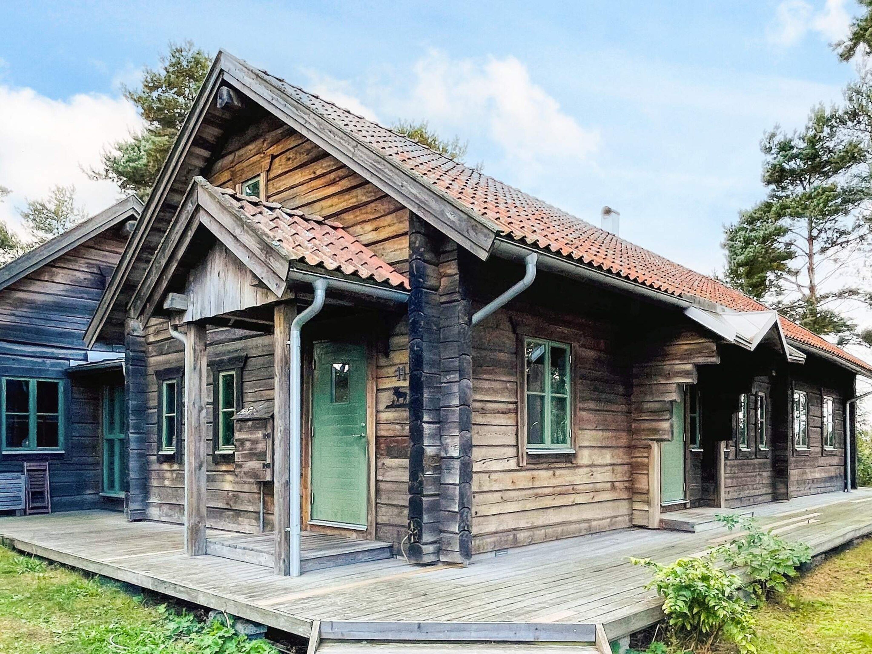 Een houten blokhut met een veranda en een pannendak.
