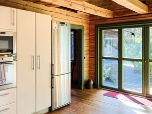 A kitchen with a stainless steel refrigerator, a built-in oven, and a wooden ceiling. - 4 Star Holiday Home in Yngsjo (Yngsjo)
