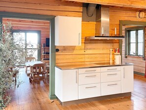 A wooden interior with a kitchen area featuring white cabinets, a wooden countertop, and a built-in stove.