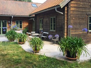 A wooden cabin with a tiled roof, outdoor seating, and potted plants. - 4 Star Holiday Home in Yngsjo (Yngsjo)