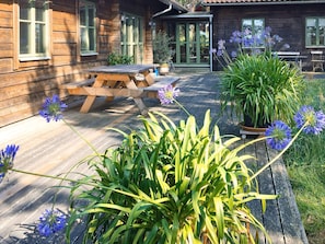 A wooden cabin with a patio, outdoor seating, and potted plants. - 4 Star Holiday Home in Yngsjo (Yngsjo)