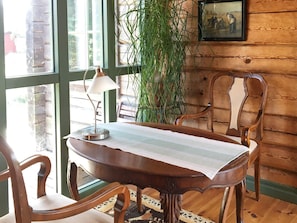 A wooden dining table with a striped tablecloth, surrounded by wooden chairs, a floor lamp, and a large potted plant. - 4 Star Holiday Home in Yngsjo (Yngsjo)