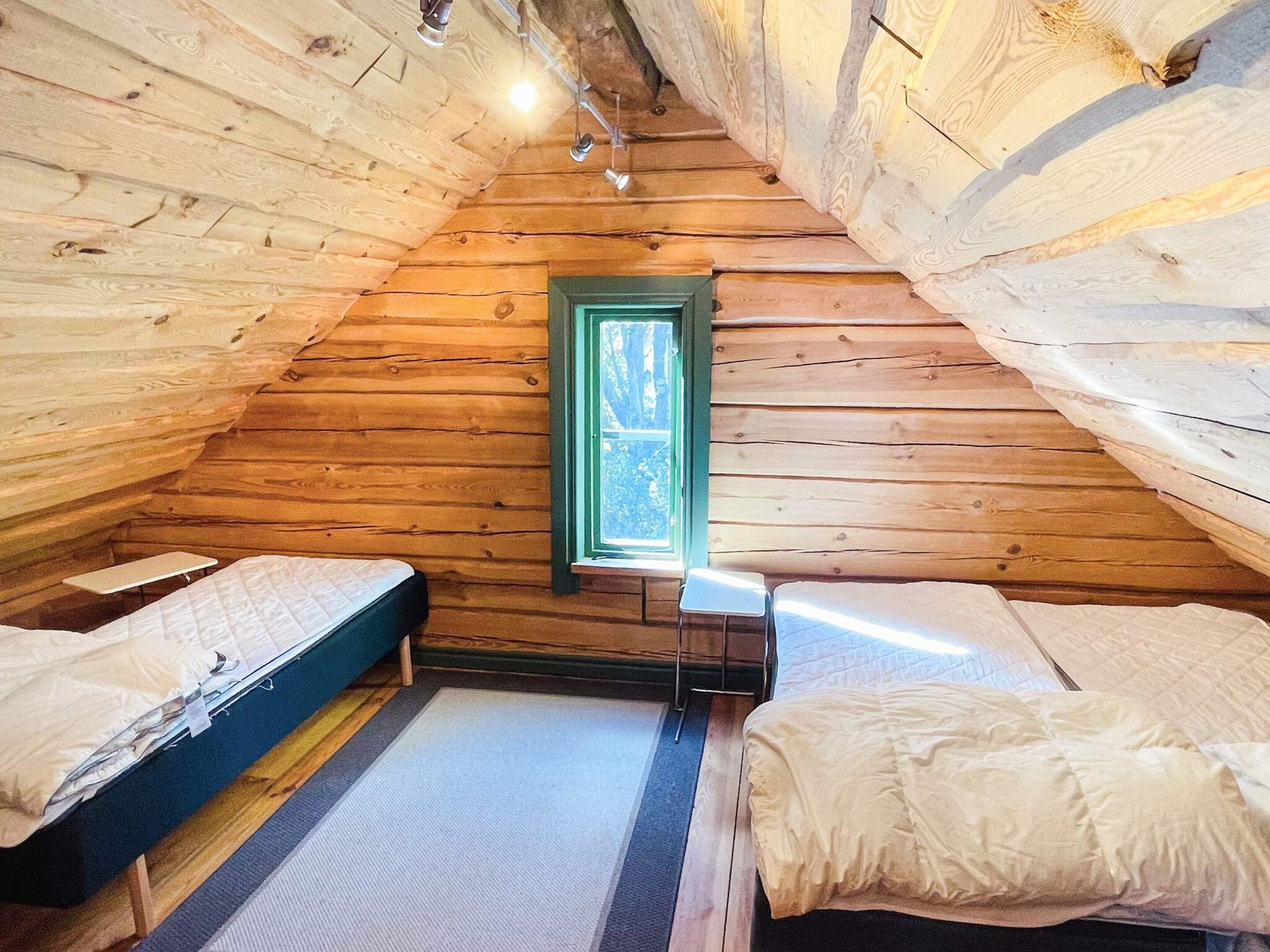 Une petite cabane en bois avec deux lits et une fenêtre.