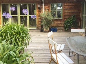 A wooden deck with a white bench, a table, and potted plants. - 4 Star Holiday Home in Yngsjo (Yngsjo)