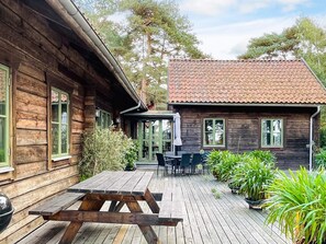 A wooden cabin with a tiled roof, a wooden deck, and a picnic table. - 4 Star Holiday Home in Yngsjo (Yngsjo)