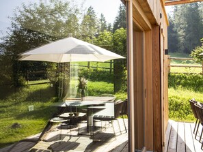 An outdoor patio with a table and chairs, a large umbrella, and a wooden deck. - Spacious Chalet in Wolting With Sauna (Tamsweg)