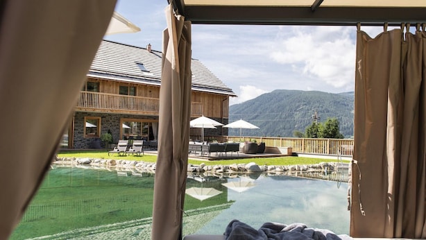 A bedroom with a view of a pool, outdoor seating, and a mountain backdrop. - Spacious Chalet in Wolting With Sauna (Tamsweg)