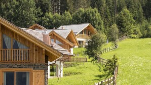 A row of wooden cabins with stone foundations, set on a grassy hillside with a wooden fence in the foreground. - Spacious Chalet in Wolting With Sauna (Tamsweg)