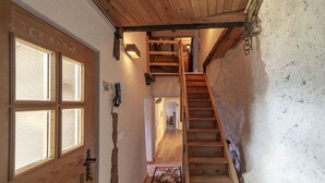 A wooden staircase leading to an upper floor, a door with frosted glass panels, and a patterned rug on the floor.